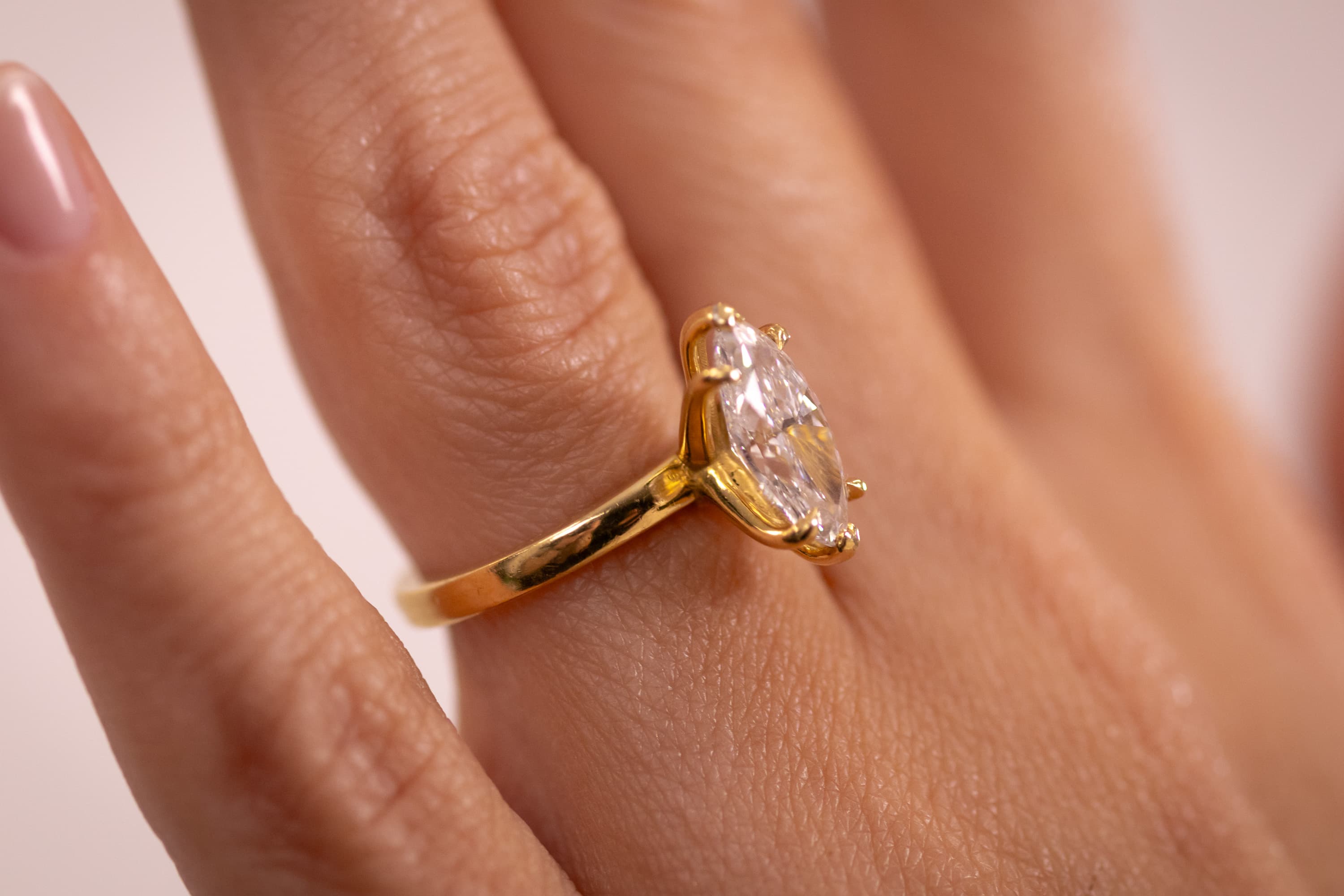 Close-up of a bezel-set oval lab-grown diamond ring in yellow gold