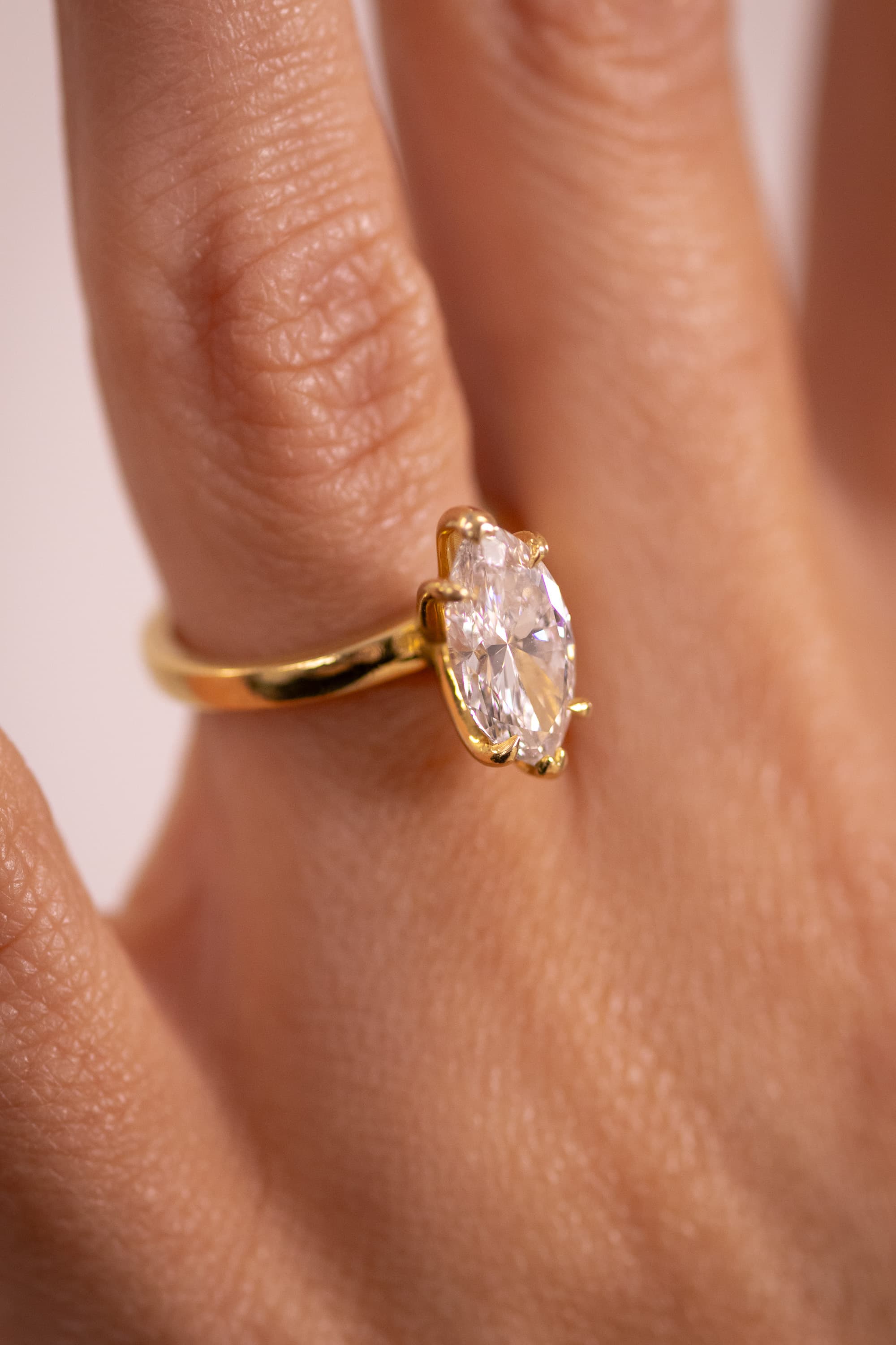 A marquise-cut diamond solitaire in a yellow gold band, worn on a hand