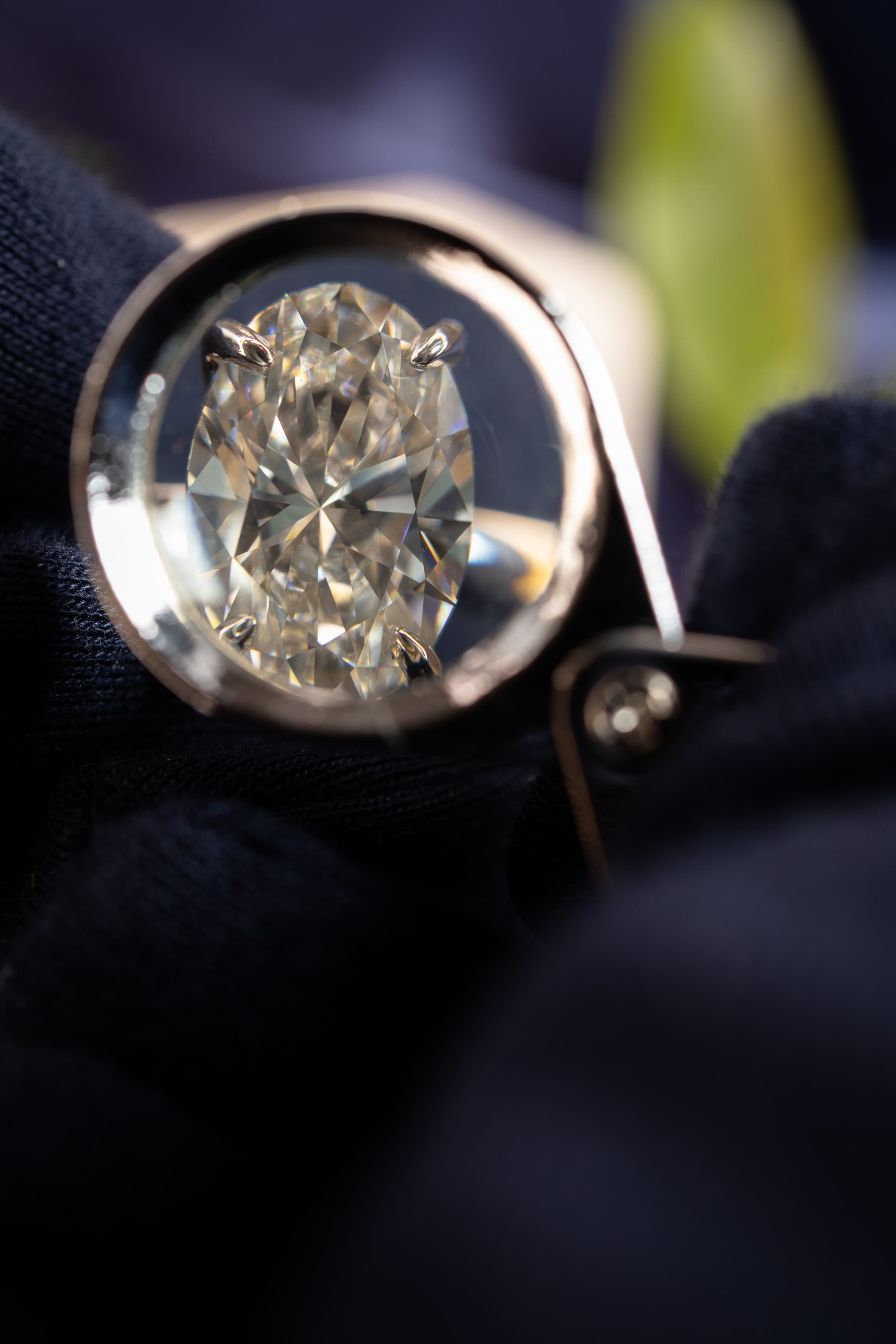 A loose round brilliant diamond held in tweezers beside a grading loupe