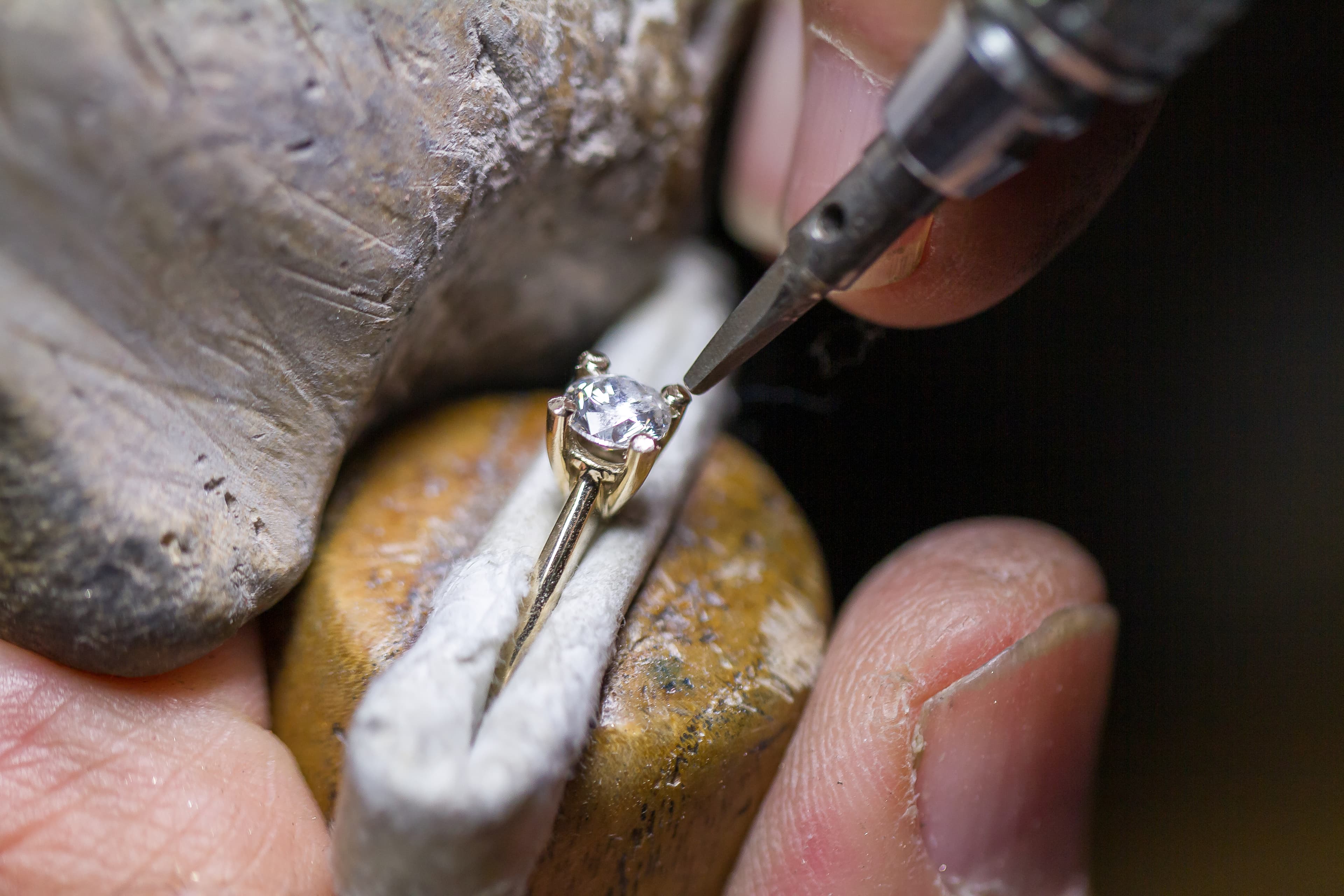 A jeweller polishing an engagement ring on a rotary polishing wheel at the workbench